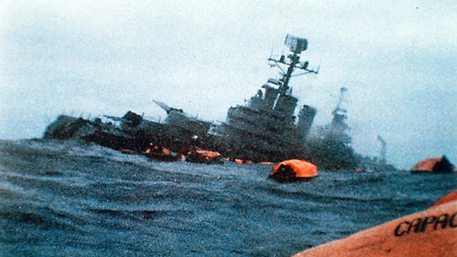 El crucero ARA General Belgrano listando en el Atlántico Sur, 2 de mayo de 1982, con balsas de salvamento anaranjadas en el agua.